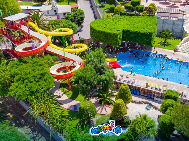 Vista panorámica del Parque Acuático El Tephé, con albercas de agua cristalina, toboganes y áreas recreativas rodeadas de vegetación y palapas.