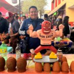 Puesto de Cantaritos Don Chuy en feria, con exhibición de jarros de barro y figura de luchador como elemento distintivo de la marca.