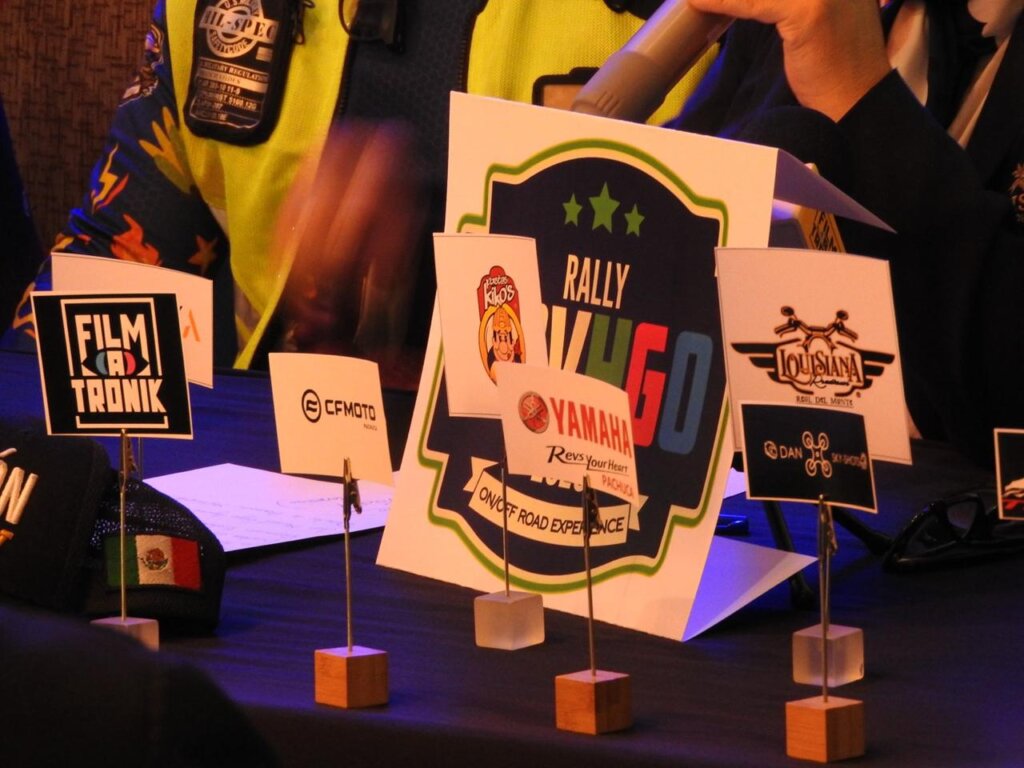 Logotipo del Rally ADV Hidalgo 2026 en mesa de conferencia rodeado de patrocinadores del evento como Yamaha, CFMOTO y Louisiana, durante presentación oficial.