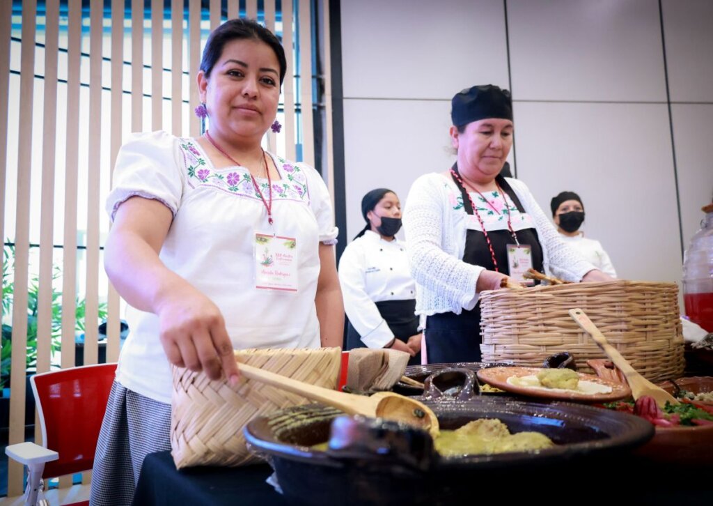 Cocineras tradicionales y participantes posan junto a platillos típicos como tamales y guajolote con escamoles durante la presentación de la XLV Muestra Gastronómica de Santiago de Anaya en Hidalgo.