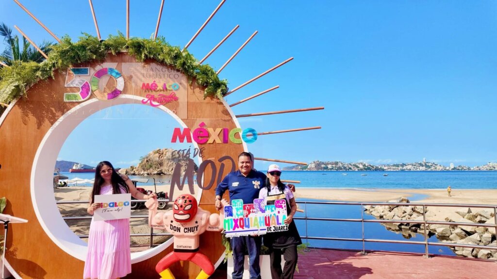 Representantes de Cantaritos Don Chuy posan en Acapulco durante Ventana México 2026, frente al mar y al arco conmemorativo del Tianguis Turístico, promoviendo a Hidalgo.