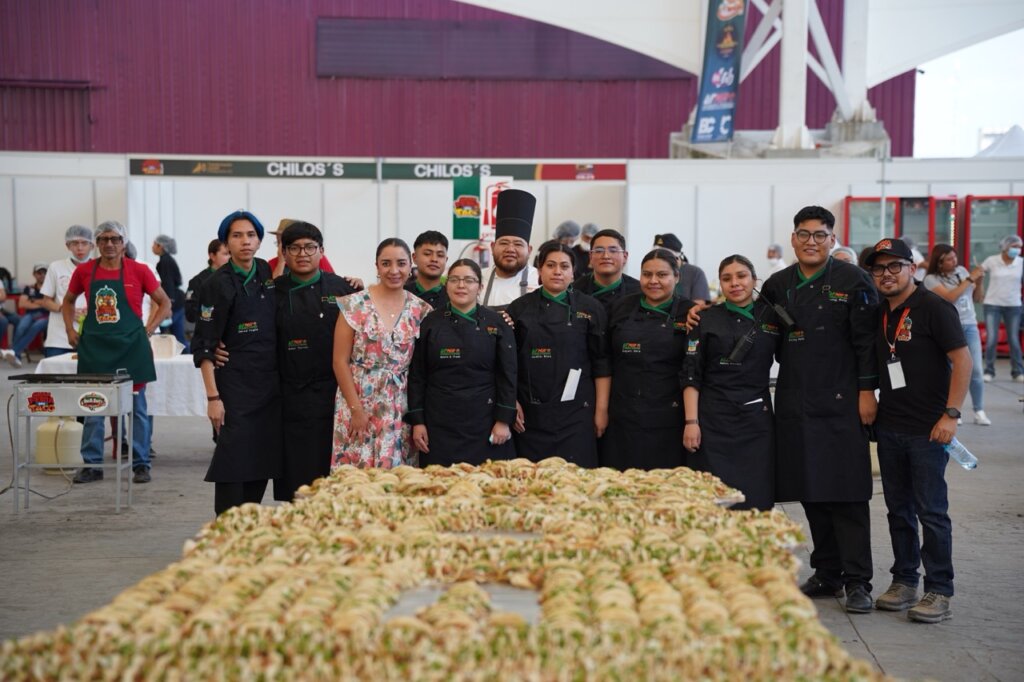 Equipo de chefs, estudiantes y organizadores posa frente a la estructura monumental de tacos elaborada para obtener el Récord Guinness durante la Gran Feria del Taco 2026 en Pachuca. 