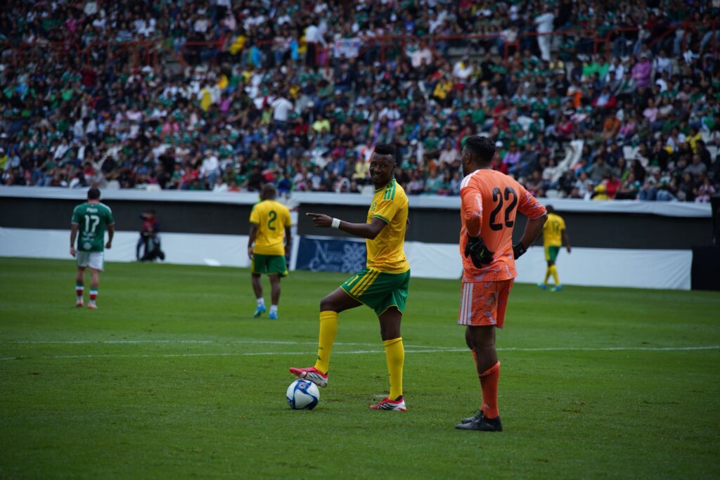 Jugador de la selección de leyendas de Sudáfrica controla el balón durante el partido amistoso ante México en el Estadio Hidalgo, mientras miles de aficionados observan el encuentro desde las tribunas como parte de las actividades rumbo al Mundial 2026. (Foto: Edgar Torres)