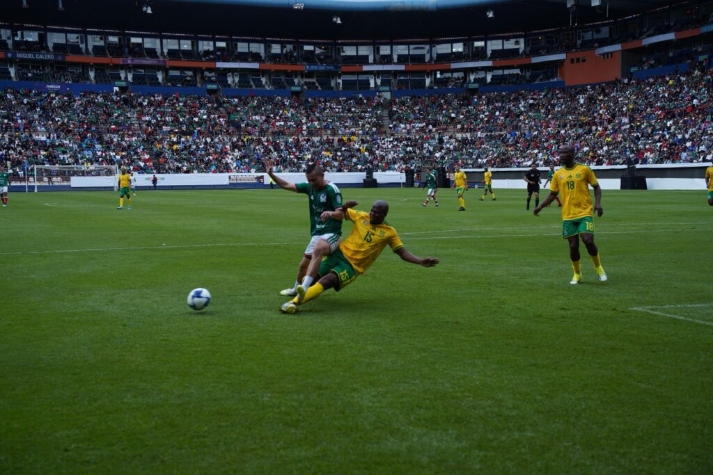Partido de leyendas entre México y Sudáfrica en el Estadio Hidalgo, donde un jugador mexicano disputa el balón ante un exseleccionado sudafricano frente a miles de aficionados que llenaron las tribunas durante las actividades rumbo al Mundial 2026. (Foto: Edgar Torres)