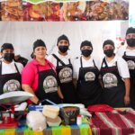 Equipo de barbacoyeras y barbacoyeros posa frente a su puesto durante el Segundo Festival de la Barbacoa del Valle del Mezquital.