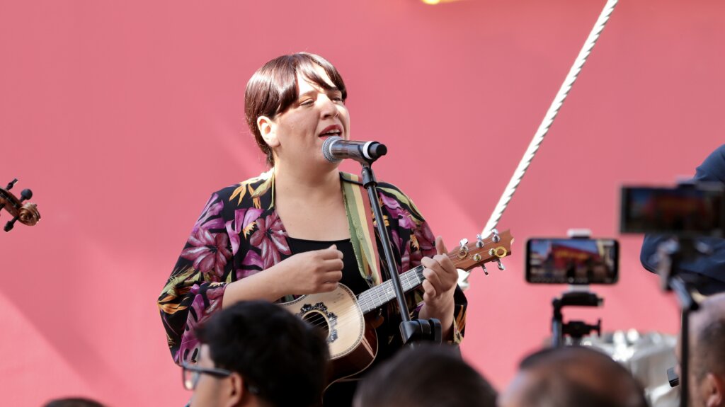 Integrante de Son de Kalunga canta y toca un instrumento durante una presentación musical ante el público.